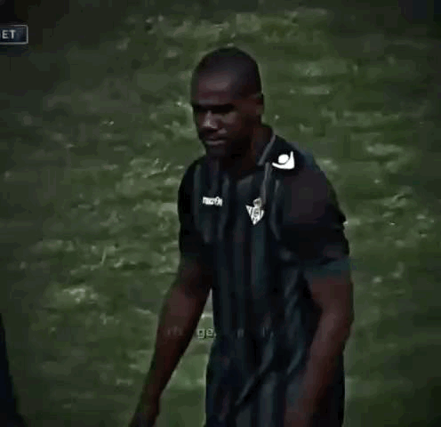 Man in Striped Shirt Talking to Another Man on Soccer Field