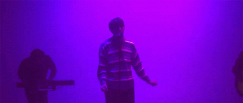 Man in Striped Sweater in Front of Purple Wall