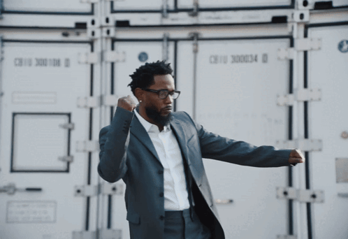 Man in Suit and Glasses in Front of Cargo Container