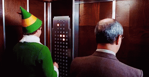 Man in Suit and Green Hat Elf in Elevator