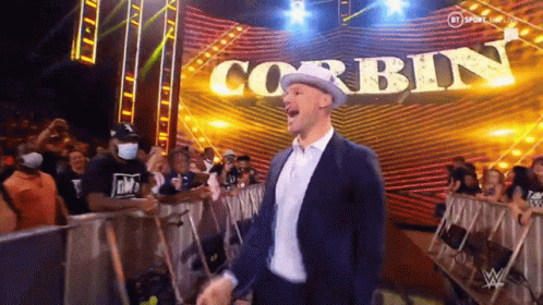 Man in Suit and Hat Standing in Front of Stage With Corbin