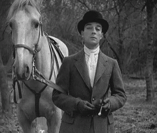 Man In Suit And Hat Standing Next To Horse GIF