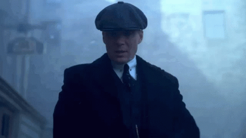 Man In Suit And Hat Walking Through Foggy Street GIF