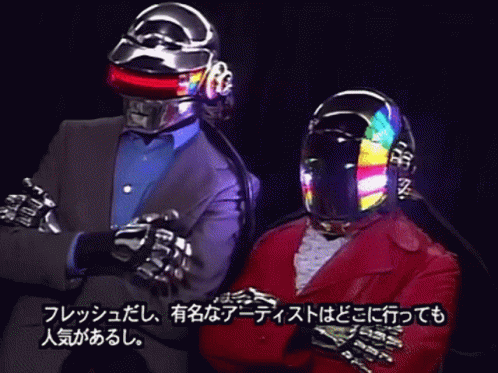 Man in Suit and Helmet Next to Man With Arms Crossed