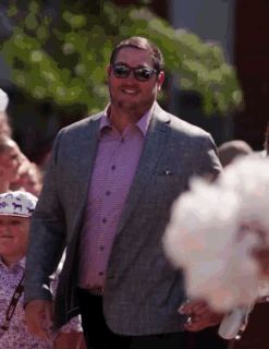 Man in Suit and Sunglasses Walking Before Crowd