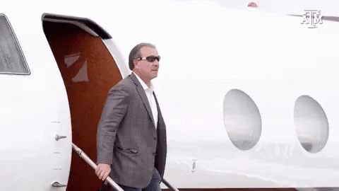 Man in Suit and Sunglasses Walking Out of Airplane