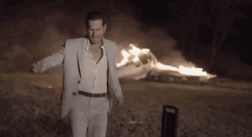 Man in Suit and Suspenders Before Burning Car