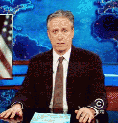 Man In Suit And Tie At Desk With Comedy Central Jacket GIF
