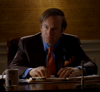 Man in Suit and Tie at Desk with Poof