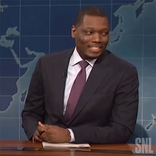 Man in Suit and Tie at Desk with SNL Logo