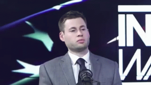 Man in Suit and Tie at Microphone Saying In