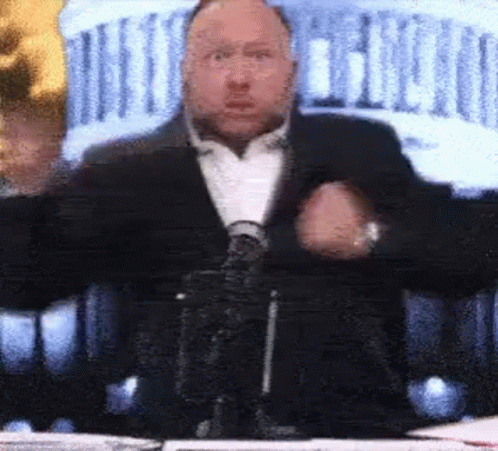 Man In Suit And Tie At Table With Microphone GIF
