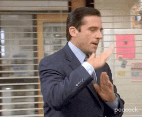 Man in Suit and Tie Clapping Hands in Front of Window With Blinds