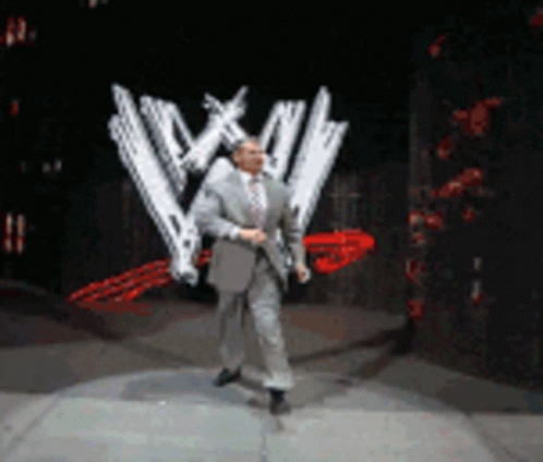Man In Suit And Tie Dancing In Front Of WWE Logo GIF