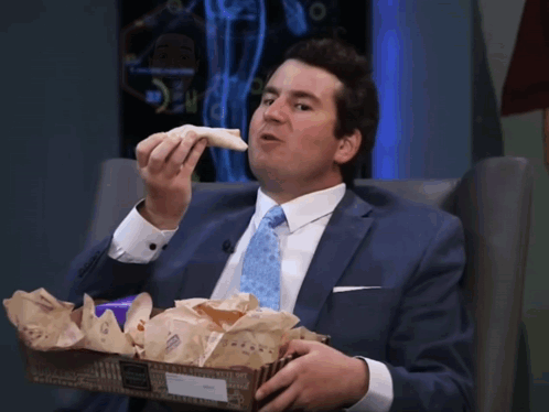 Man in Suit and Tie Eating Sandwich from Box