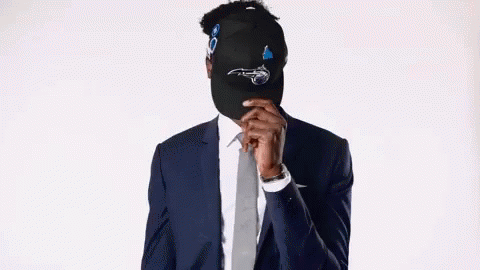 Man in Suit and Tie Hiding Face Behind Hat