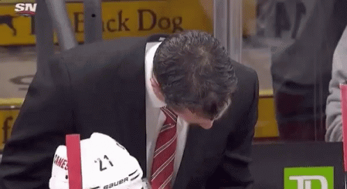 Man in Suit and Tie Holding Bauer Hockey Helmet