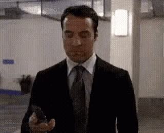 Man in Suit and Tie Holding Cellphone Hallway