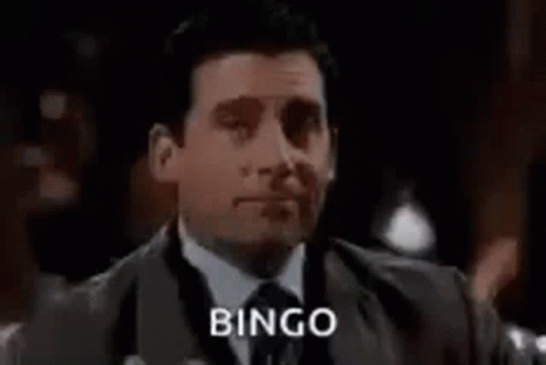 Man in Suit and Tie Holding Drink Saying Bingo