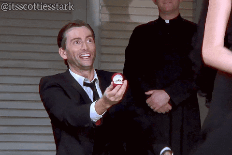 Man in Suit and Tie Holding Engagement Ring to Woman