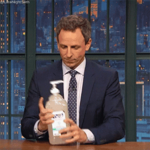 Man In Suit And Tie Holding Hand Sanitizer GIF