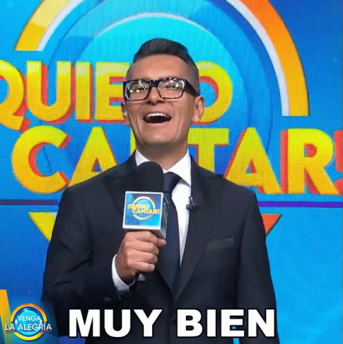Man in Suit and Tie Holding Microphone Beside Muy Bien Sign