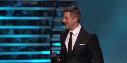 Man in Suit and Tie Holding Microphone on Stage