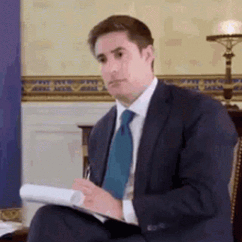 Man in Suit and Tie Holding Paper and Pen