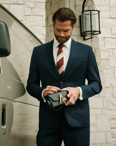 Man In Suit And Tie Holding Small Black Purse GIF