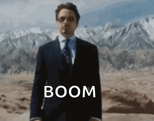 Man In Suit And Tie In Desert With Word Boom GIF