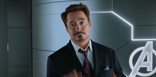 Man In Suit And Tie In Front Of Avengers Sign GIF