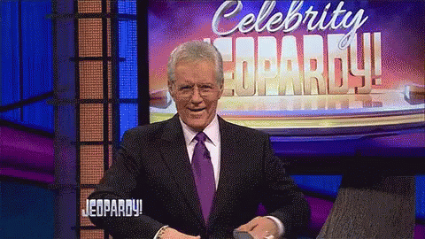 Man in Suit and Tie in Front of Celebrity Jeopardy Sign