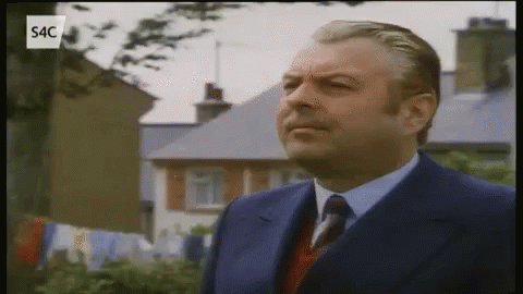 Man in Suit and Tie in Front of Houses