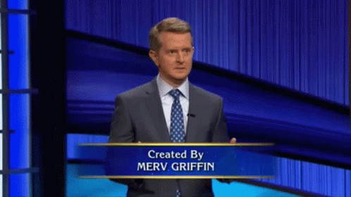 Man in Suit and Tie in Front of Merv Griffin Sign