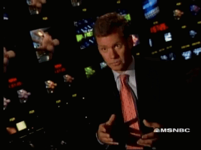 Man in Suit and Tie in Front of MSNBC Screens