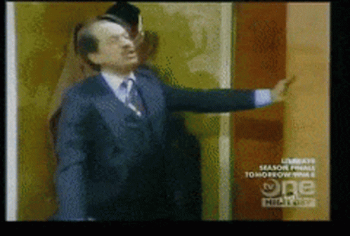 Man in Suit and Tie in Front of TV Wall