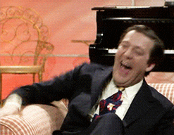 Man in Suit and Tie Laughing at Piano