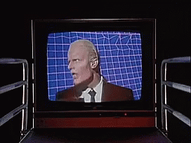 Man In Suit And Tie Laughing On TV GIF