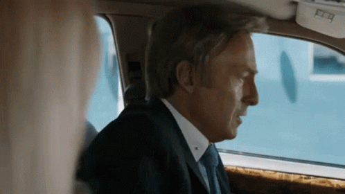 Man in Suit and Tie Looking Out Car Window