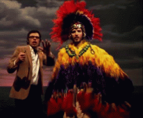 Man in Suit and Tie Next to Feathered Costume