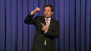Man in Suit and Tie on Stage With Blue Curtain