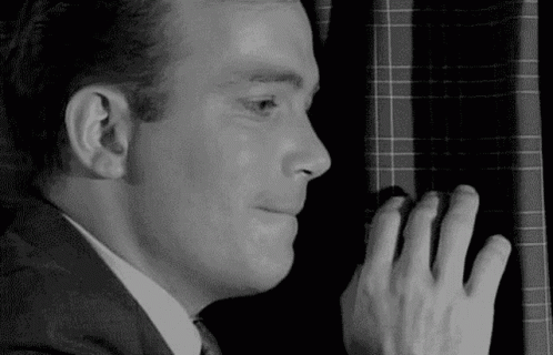 Man in Suit and Tie Peeking Behind Window