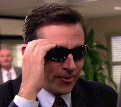 Man in Suit and Tie Putting on Sunglasses
