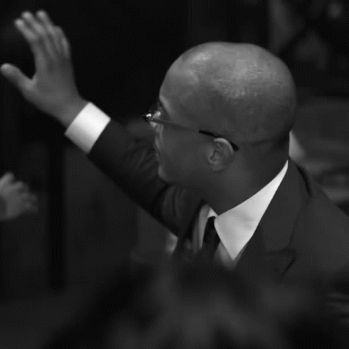 Man in Suit and Tie Raising Hand
