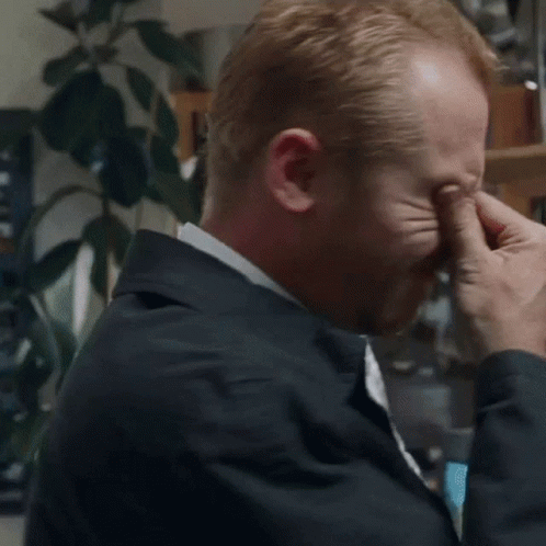 Man in Suit and Tie Rubbing Eyes