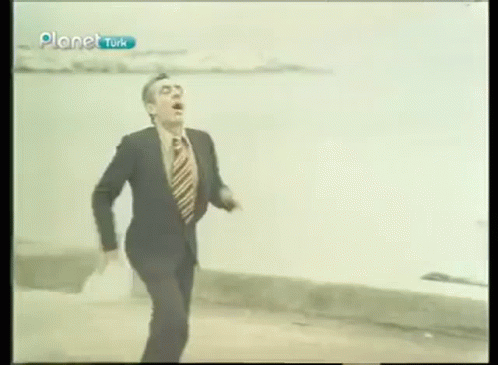 Man in Suit and Tie Running Across Street