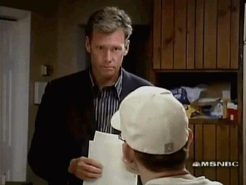 Man In Suit And Tie Saying Have A Seat GIF