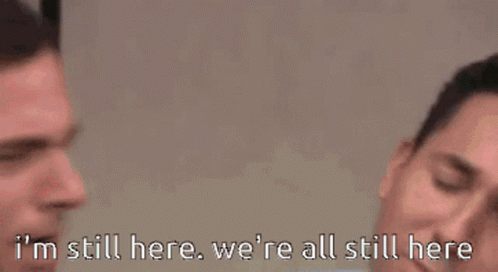 Man In Suit And Tie Saying I'm Still Here, We're All Still Here GIF