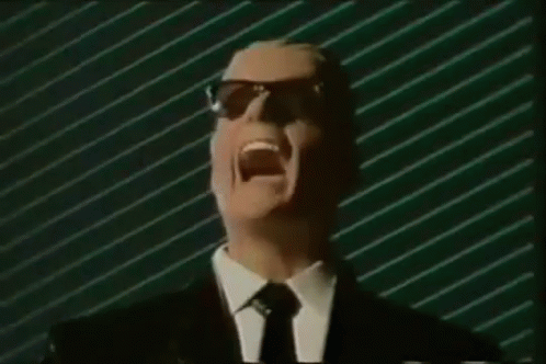 Man In Suit And Tie Screaming Into Mic With Sunglasses GIF