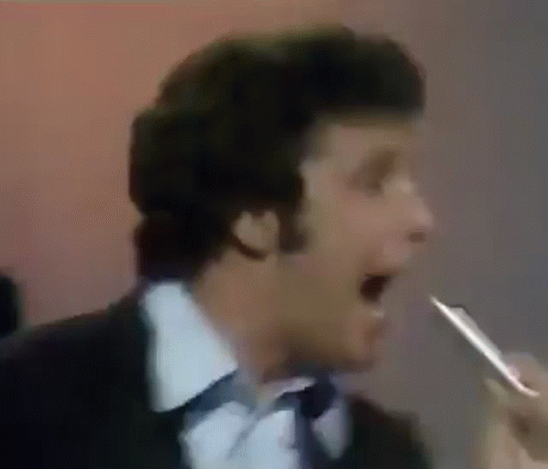 Man In Suit And Tie Singing Into Microphone Holding Pen GIF